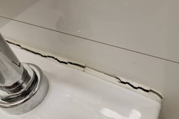 toilet in bathroom or restroom with crack in the wall or caulk