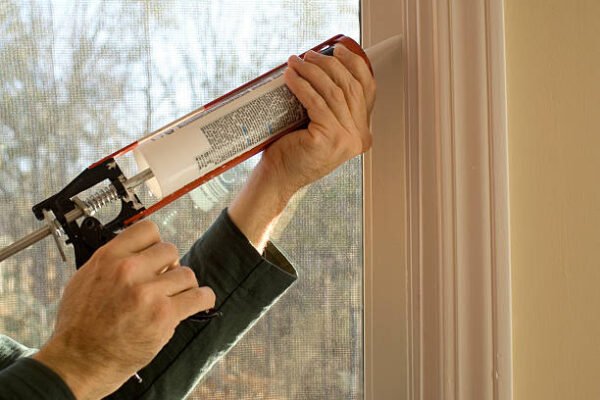 man caulking window during the day